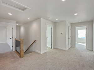 Corridor with light colored carpet and a textured ceiling