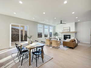 Dining space featuring a fireplace, light wood-type flooring, and ceiling fan