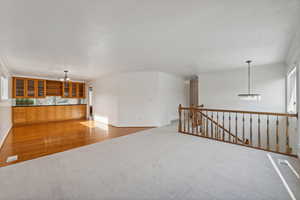 Unfurnished living room with ornamental molding, wood-type flooring, and an inviting chandelier