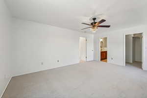 Primary bedroom with light carpet, a walk-in closet, ceiling fan, connected bathroom, and a closet