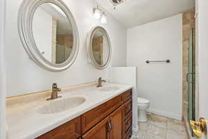 Primary bathroom with tile patterned flooring, vanity, toilet, and a shower with shower door