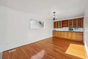 Interior space with a chandelier, pendant lighting, light hardwood / wood-style flooring, and crown molding