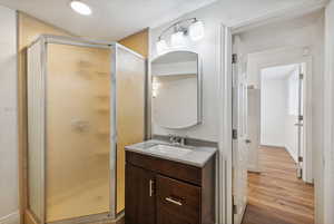 Bathroom with vanity, hardwood / wood-style flooring, and a shower with shower door