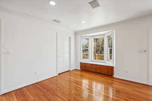 Spare room with ornamental molding and light wood-type flooring