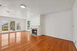 Unfurnished living room with a high end fireplace, ornamental molding, and light wood-type flooring