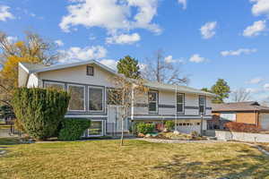 View of front of home with a garage and a front lawn