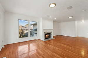 Unfurnished living room featuring a premium fireplace, crown molding, and light hardwood / wood-style flooring