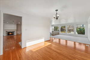 Empty room featuring radiator, an inviting chandelier, crown molding, light hardwood / wood-style flooring, and a fireplace