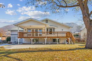 Rear view of house featuring ceiling fan, a deck with mountain view, and a yard