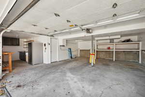 Garage featuring stainless steel fridge and a garage door opener