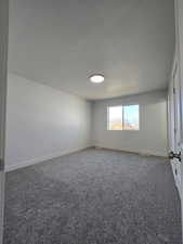 Carpeted empty room with a textured ceiling