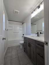 Full bathroom with tile patterned floors, vanity, a textured ceiling,  shower combination, and toilet