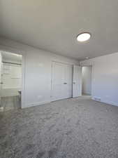 Unfurnished bedroom with carpet flooring, a textured ceiling, and connected bathroom