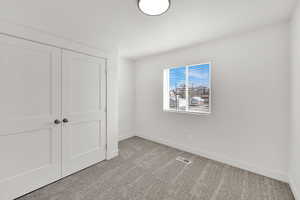 Unfurnished bedroom with light colored carpet and a closet