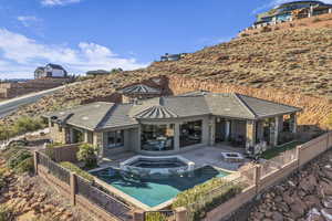 Back of property featuring a patio area and a swimming pool with hot tub