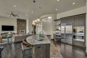 Kitchen featuring a kitchen island with sink, sink, decorative light fixtures, dark brown cabinets, and stainless steel appliances