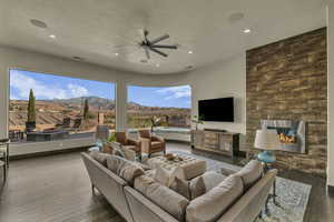 Living room with ceiling fan, dark hardwood / wood-style flooring, and a textured ceiling