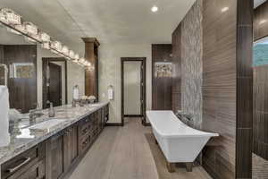 Bathroom with a tub, vanity, wood-type flooring, and tile walls