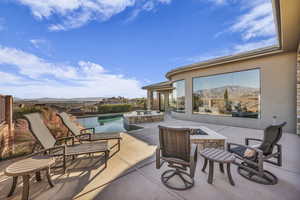 View of patio with a mountain view, a fire pit, and a pool with hot tub