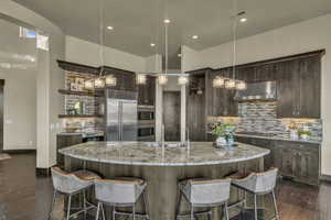 Kitchen with a large island with sink, dark hardwood / wood-style flooring, and stainless steel appliances