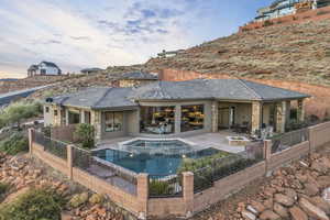 Pool at dusk with an in ground hot tub and a patio