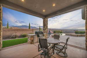 Patio terrace at dusk featuring a mountain view, a pool, and exterior kitchen