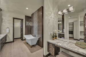 Bathroom with a bathing tub, vanity, and wood-type flooring