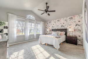 Carpeted bedroom with ceiling fan and vaulted ceiling