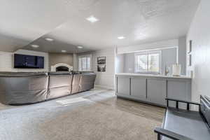 Interior space featuring a brick fireplace, a textured ceiling, light hardwood / wood-style flooring, and wooden walls