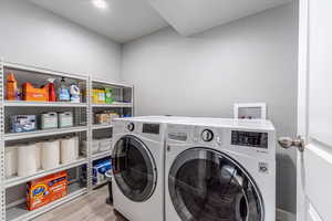 Laundry area with light wood-type flooring and washing machine and clothes dryer