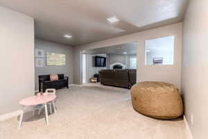 Living area featuring carpet flooring and a textured ceiling