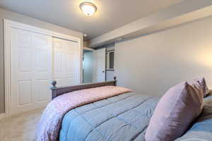 Carpeted bedroom featuring a textured ceiling and a closet