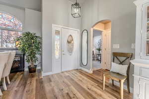 Foyer entrance featuring a high ceiling, a notable chandelier, and wood-type flooring