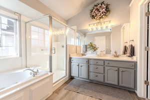 Bathroom featuring hardwood / wood-style flooring, vanity, lofted ceiling, and shower with separate bathtub