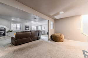 Carpeted living room featuring a textured ceiling and a brick fireplace