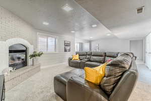 Carpeted living room with a fireplace and a textured ceiling