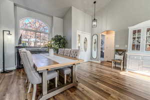 Dining room with high vaulted ceiling and dark wood-type flooring