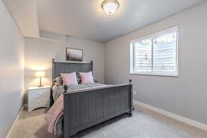 Bedroom with a textured ceiling and light colored carpet