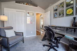 Carpeted office featuring a textured ceiling and vaulted ceiling