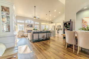 Living room with a tile fireplace, ceiling fan, high vaulted ceiling, and light hardwood / wood-style floors