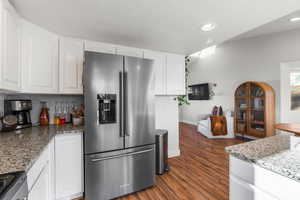 Kitchen featuring white cabinets, stone counters, stove, dark hardwood / wood-style flooring, and high end refrigerator