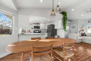 Dining area with ceiling fan, vaulted ceiling, and wood-type flooring