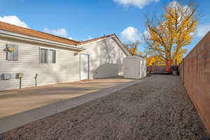 View of side of property with a patio and a storage unit