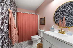 Bathroom with a shower with shower curtain, tile patterned flooring, vanity, and toilet