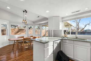 Kitchen with white cabinets, a textured ceiling, dishwasher, vaulted ceiling, and dark hardwood / wood-style floors