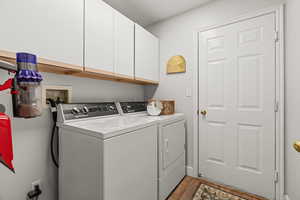 Laundry room with light hardwood / wood-style floors, cabinets, and separate washer and dryer