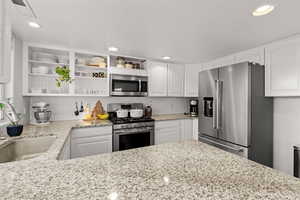 Kitchen with white cabinets, sink, appliances with stainless steel finishes, and a textured ceiling