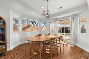 Dining space with hardwood / wood-style floors, vaulted ceiling, and plenty of natural light