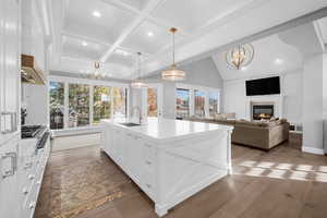 Kitchen with pendant lighting, a center island with sink, sink, dark hardwood / wood-style floors, and white cabinetry