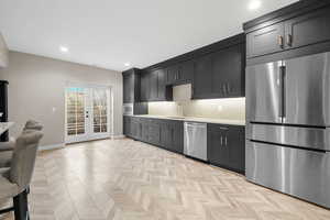 Kitchen featuring french doors, sink, tasteful backsplash, stainless steel appliances, and light parquet flooring